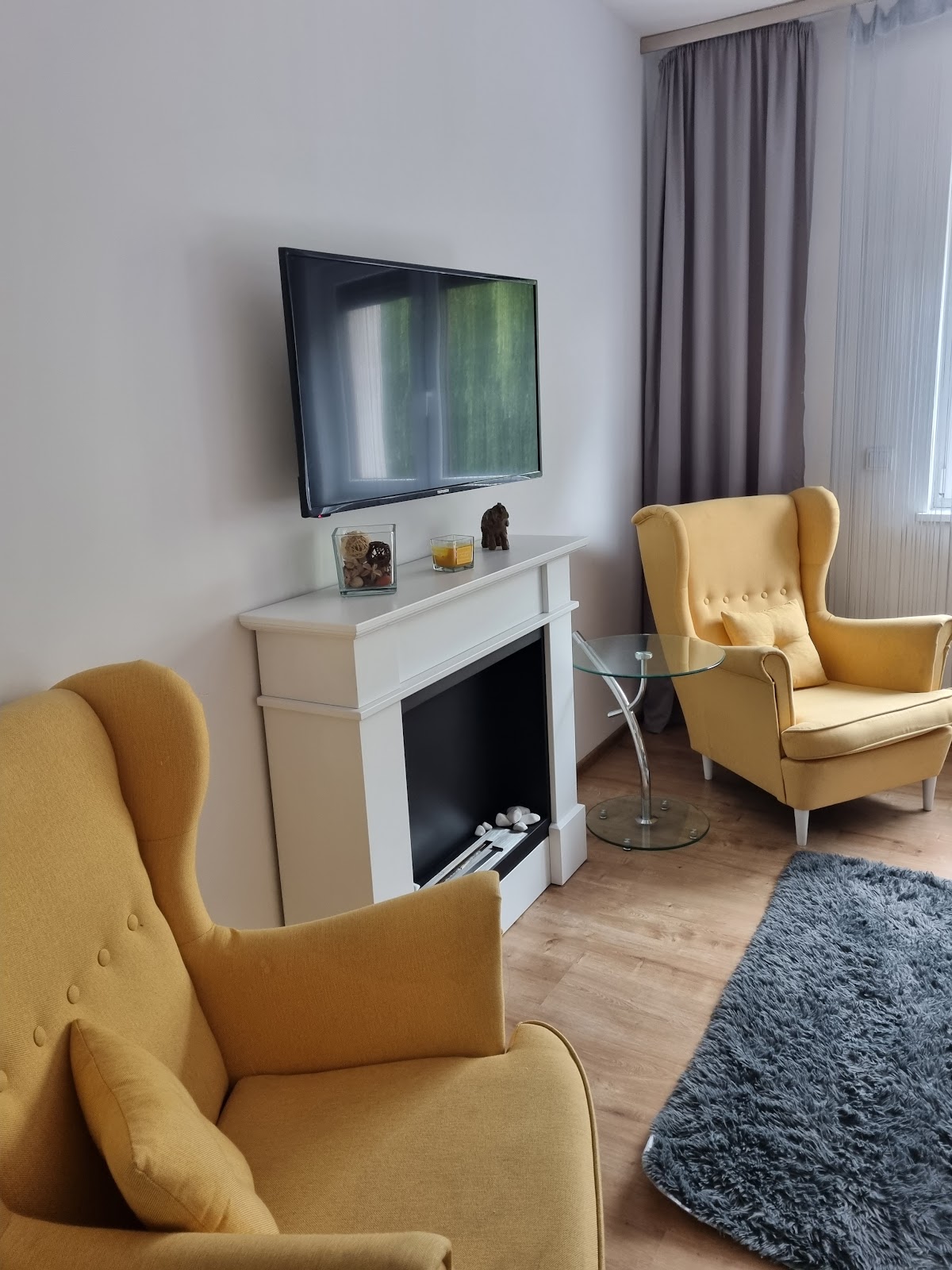 Salon Apartamentu Vasco z żółtymi fotelami usznymi i białym kominkiem